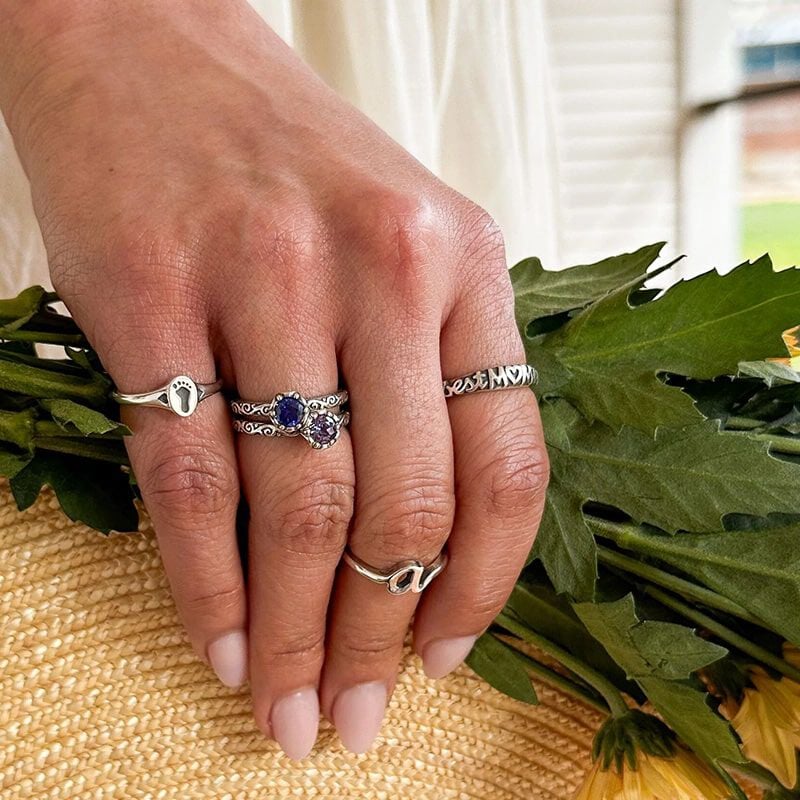 A hand holding flowers and wearing sterling silver rings.
