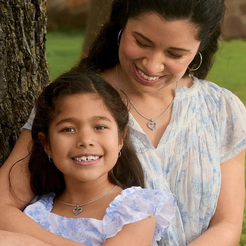 A mother and daughter wearing sterling silver heart-shaped pendants.