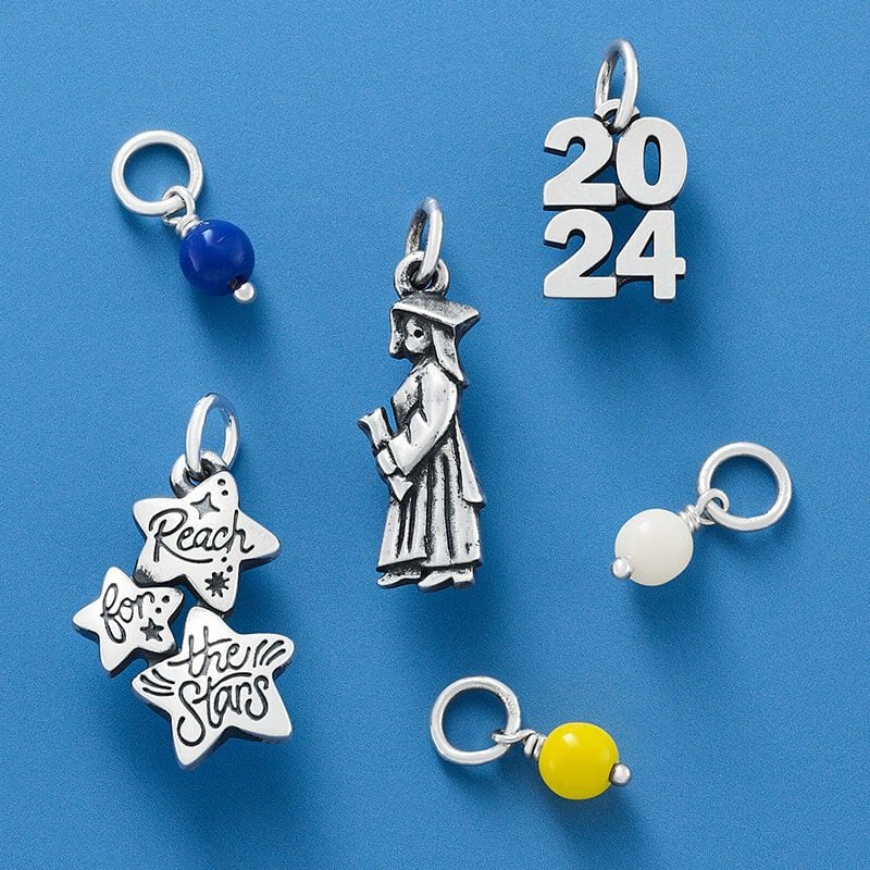 Graduation-themed sterling silver and enamel charms on a blue background.