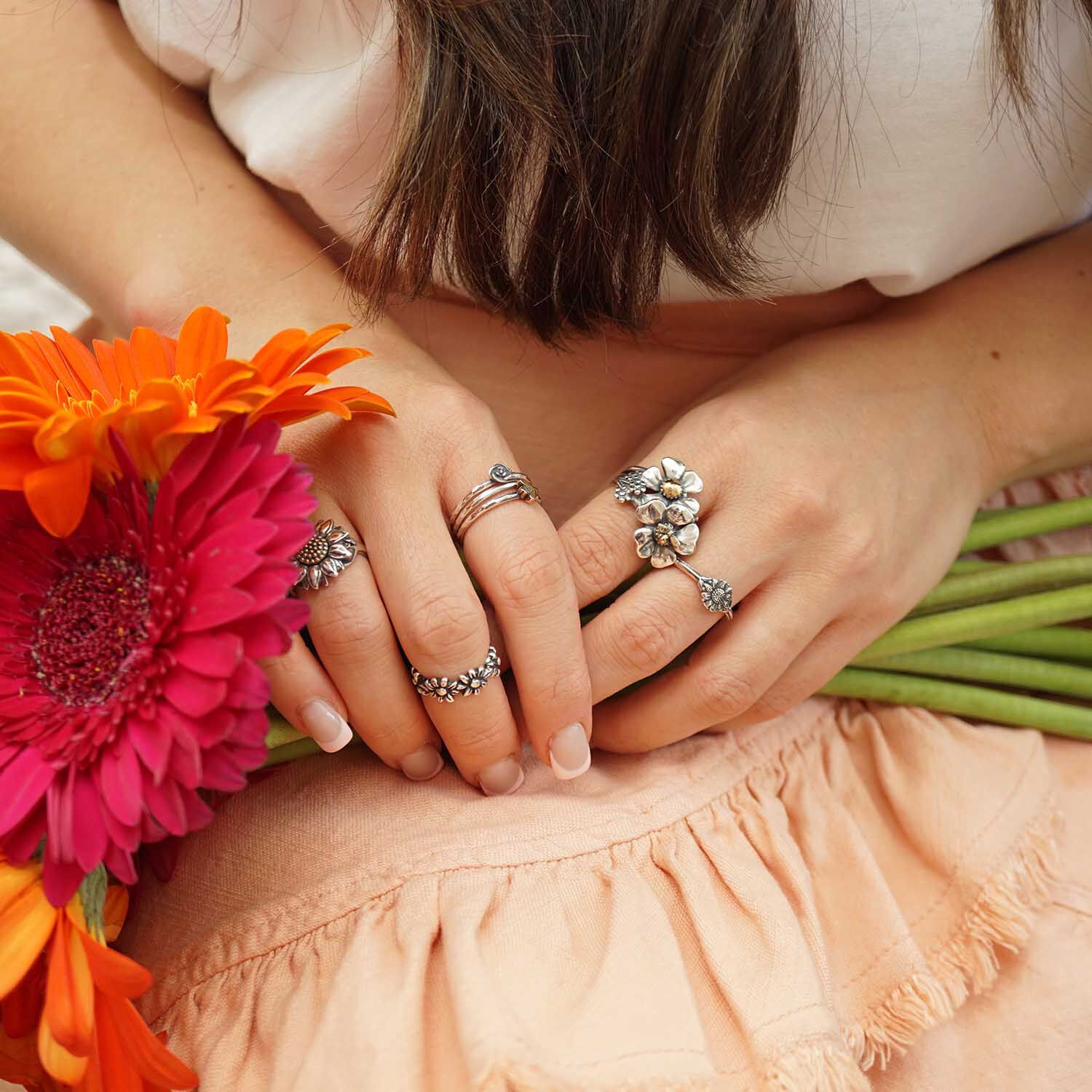 Hand holding flowers and wearing sterling silver rings from James Avery.