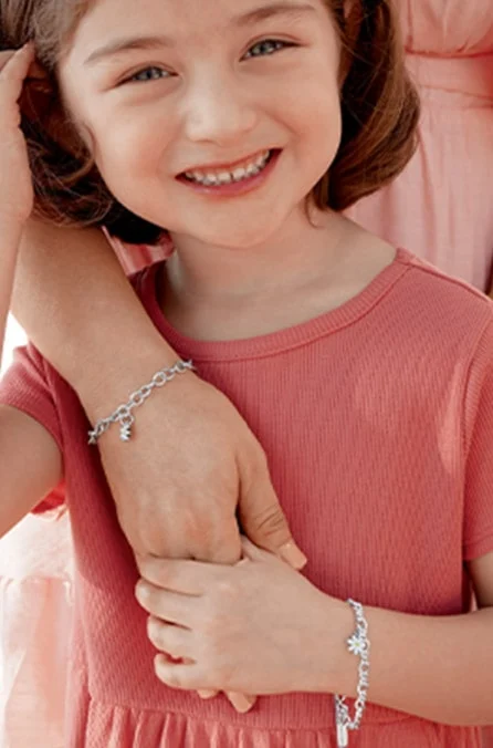 Child wearing a sterling silver bracelet, holding her mother’s hand.