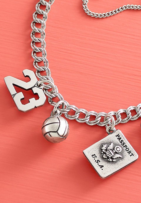 Two sport-themed charms and the Passport Charm on a charm bracelet.